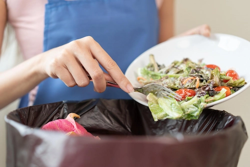 Ibu rumah tangga itu sedang membuang sisa makanan ke tempat sampah