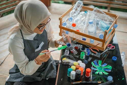 Seorang perempuan membuat kerajinan dari barang bekas dalam rangka merdeka dari sampah untuk menyambut Hari Kemerdekaan 17 Agustus