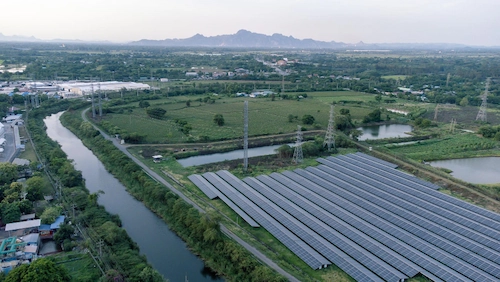 Kumpulan panel surya di tepi sungai pada kawasan industri sebagai bentuk pemanfaatan energi hijau