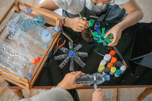 Seorang wanita mendaur ulang botol plastik menjadi kerajinan tangan