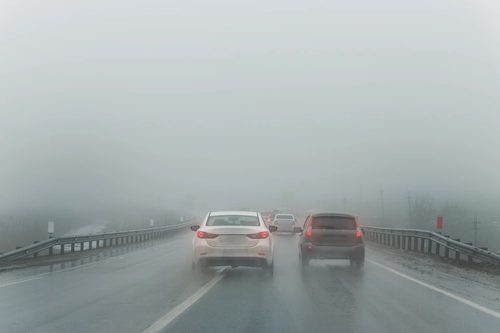 dua mobil di jalanan yang tertutup kabut abu vulkanik