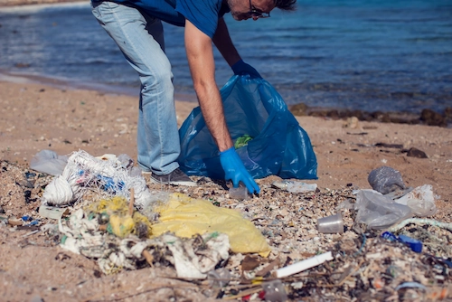 Seorang pria membawa kantong besar untuk mengumpulkan sampah di pantai