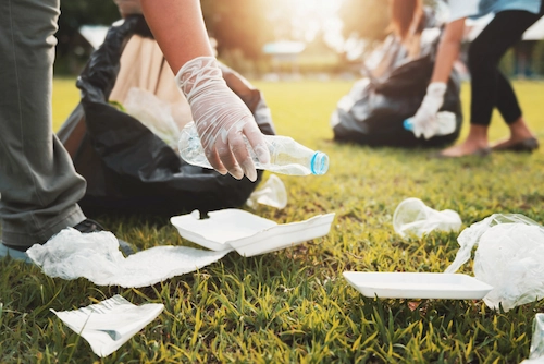 Seseorang memasukkan sampah botol plastik ke dalam kantong hitam